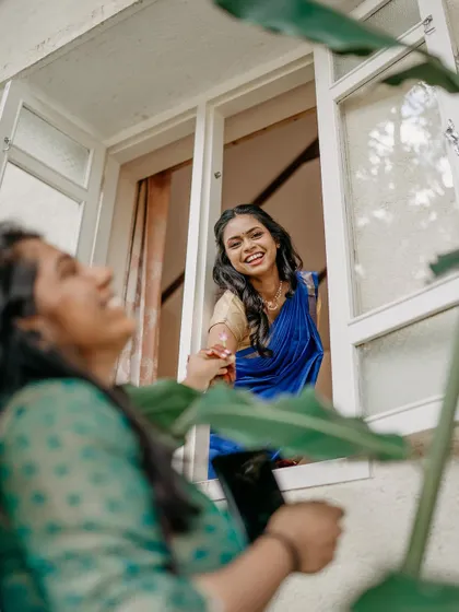 A candid shot of the bride sharing a laugh with a friend, seen through a window.