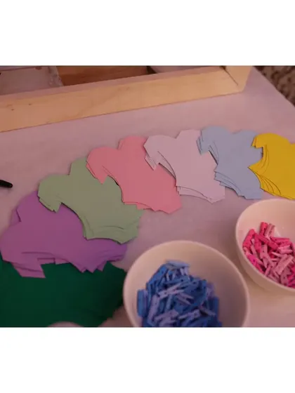A "Wishes for the Baby" activity station, where guests could write messages on colorful onesie-shaped cards and hang them up for the parents-to-be.