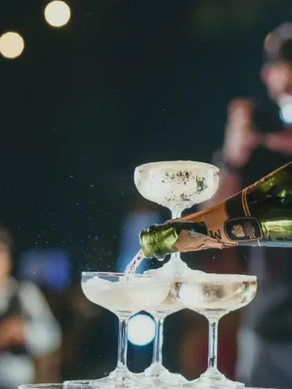 A close-up of a champagne tower being poured, capturing the spray and bubbles that signify a true celebration.