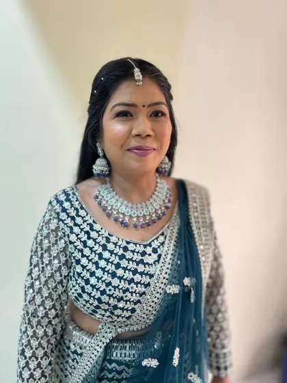 A happy client in a beautiful teal blue lehenga, paired with a diamond and sapphire jewellery set.