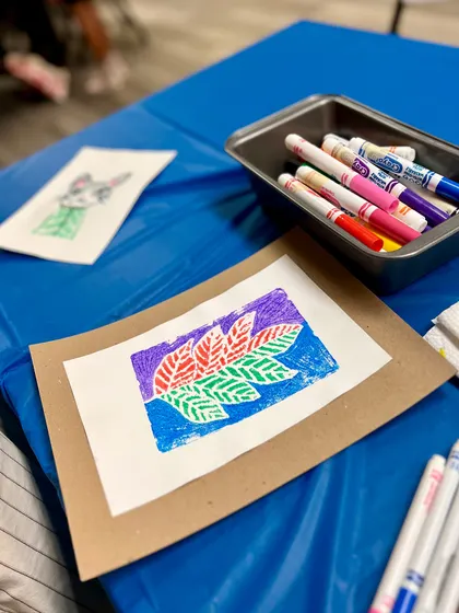 The final result of a multi-colored leaf print, sitting next to the markers used to create it.