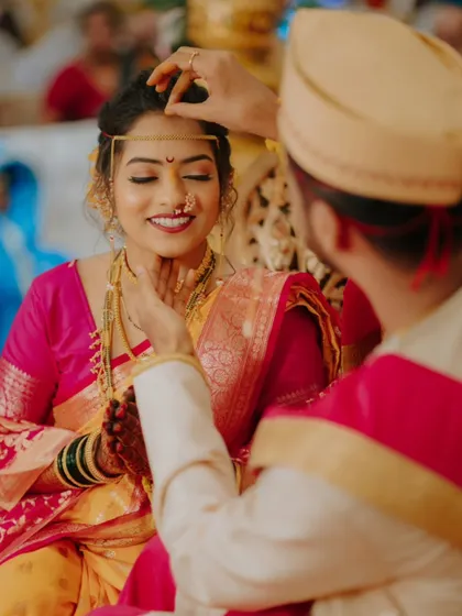 The groom gently places the 'sindoor' and 'mangalsutra', a deeply significant ritual in a Hindu wedding.