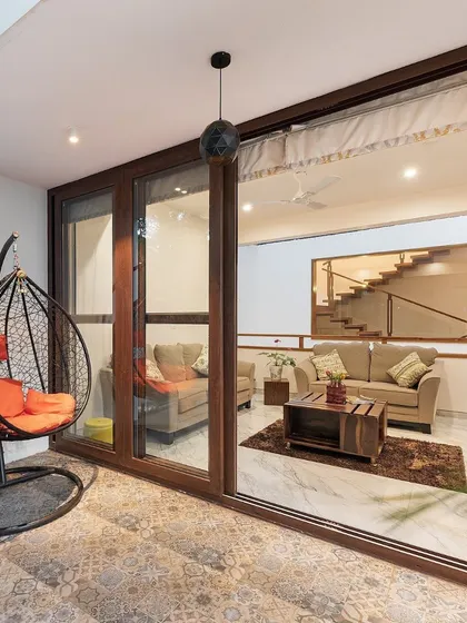 A view from the patio into the living space, highlighting the seamless indoor-outdoor connection. A hanging swing chair on the tiled patio offers a cozy nook for reading and relaxation.