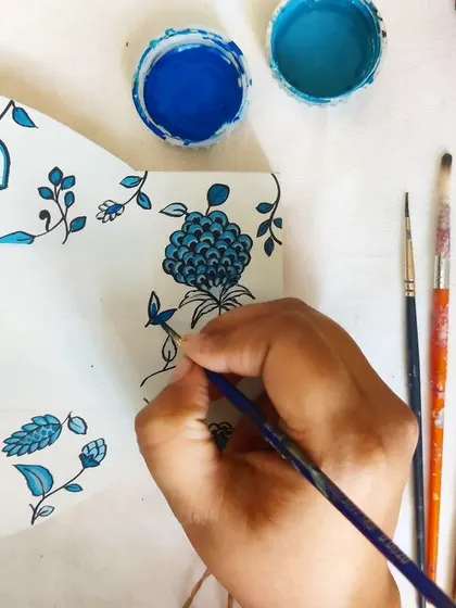 A moment of calm in the studio, painting a blue floral pattern onto a wooden nameplate. This is my therapy, getting lost in the details of each piece.