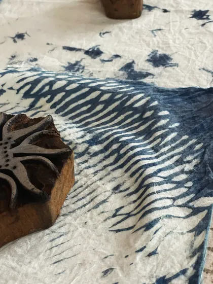 A close-up of a wooden block on indigo fabric, used to announce our dyeing and block printing workshops in Bengaluru. It's an invitation to get creative with plant-based colors.