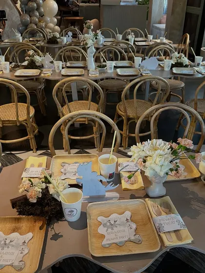 A long view of the kids' tables at the dragon-themed party, set with eco-friendly palm leaf plates, custom dragon cutouts, and simple floral centerpieces.