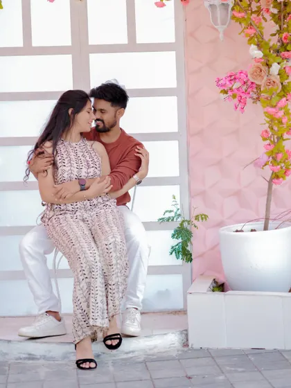 A tender moment against a romantic floral backdrop. The soft pink tones and the couple's gentle embrace create a dreamy and affectionate pre-wedding portrait.