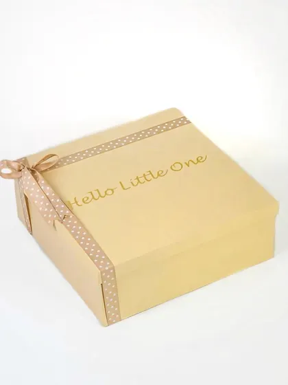 The exterior of a simple and elegant baby gift box with 'Hello Little One' in gold foil. This shot focuses on the premium packaging for an e-commerce listing.