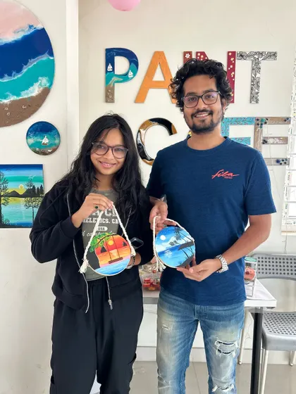 A couple proudly holds up the matching canvas paintings they created in our studio.
