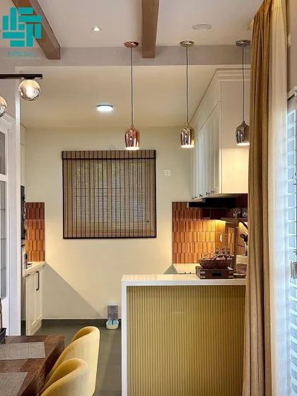 The breakfast bar, with its ribbed yellow paneling, provides a casual dining spot and a visual separation between the kitchen and dining areas. The metallic pendant lights add a touch of industrial chic.