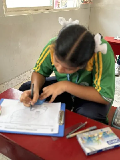 A student carefully outlines her drawing, showing great focus. We teach techniques that help children structure their art, building both their skills and their confidence.