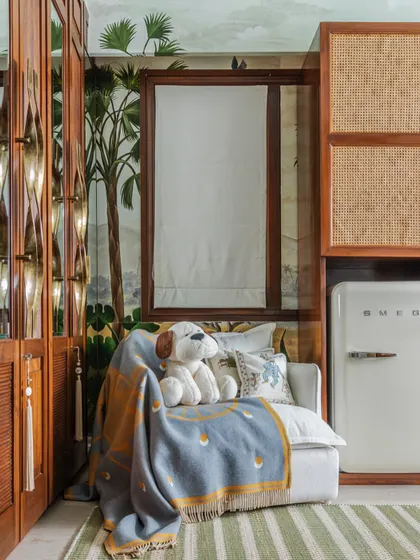 Every nursery needs a cozy corner for mom and baby. I included this comfortable armchair for feeding and story time, placed right next to the custom cane-paneled storage units.
