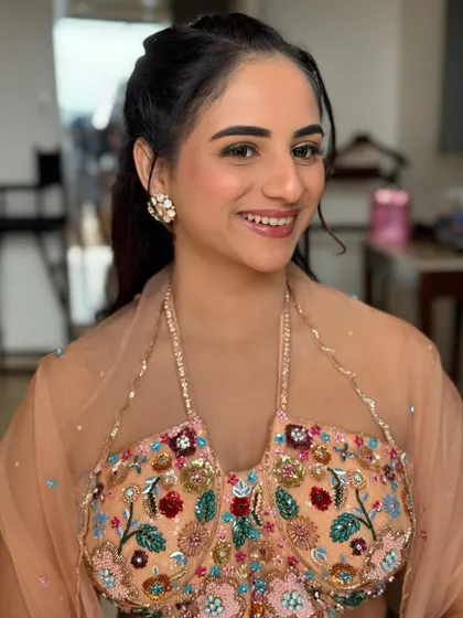 A smiling portrait of the bride, showing off her unique green eyeliner. The rest of the makeup is kept soft and peachy to balance the look.