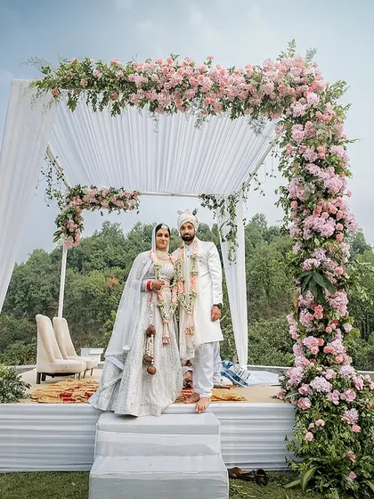 A stunning view of the couple at their floral mandap, set against a backdrop of lush green hills. This is what destination wedding dreams are made of.