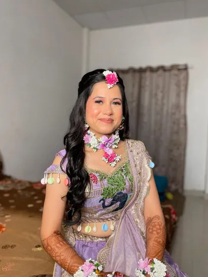 A happy, smiling bride enjoying her Haldi function. The floral jewellery adds a traditional and fragrant touch.