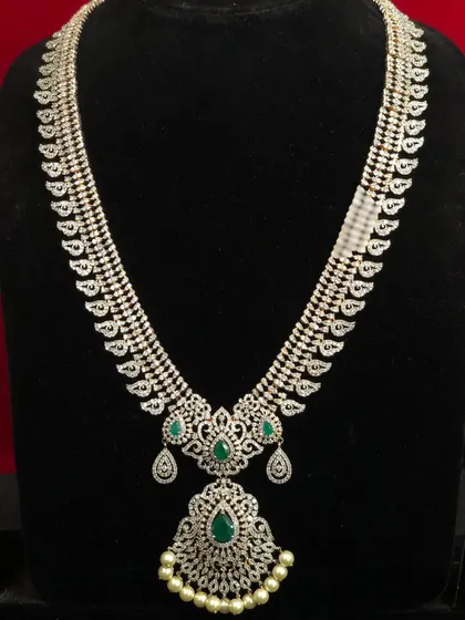 This long CZ haram with a mango design is a modern take on a traditional motif. The emerald accents and pearl drops add to its elegance.
