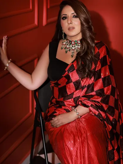 A seated pose that exudes confidence and style. The combination of the modern saree, smokey eye makeup, and heavy necklace creates a powerful fashion statement.