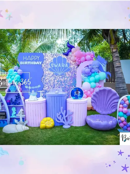The full outdoor setup for Swara's mermaid party, set against a backdrop of palm trees, with a large sequin panel and a giant clamshell.
