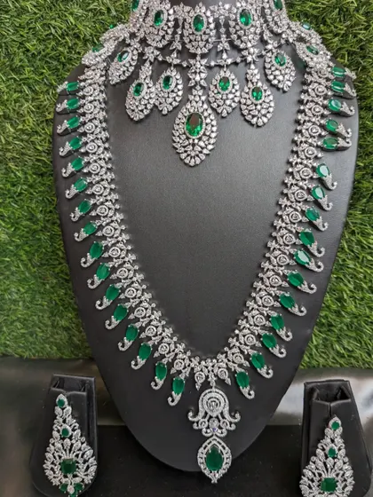 A long, single-layer Emerald American Diamond necklace paired with a heavy choker. This combination adds richness to any reception look.