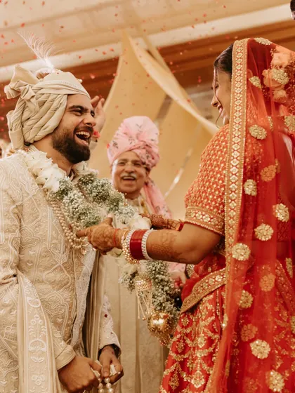 The playful and competitive spirit of the jaimala ceremony. The groom's laughter and the bride's determined smile make this a fun and memorable shot.