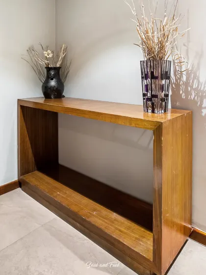A minimalist wooden console table in a hotel corridor, styled with simple vases. The clean lines and warm wood create a simple yet elegant welcome for guests at Sinclairs Hotel, Ooty.