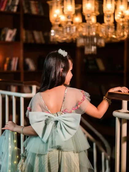 The back of a dress can be just as stunning as the front. This shot focuses on the large, elegant bow on a piece from a kids' couture collection, highlighting the craftsmanship and design details.