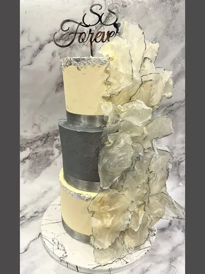 Modern sophistication for an engagement party. This three-tier cake combines a sleek grey middle tier with textured buttercream and a dramatic cascade of edible wafer paper sails.
