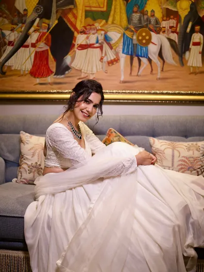 A relaxed and happy pose on a couch, showing a more candid side while still looking elegant in the white lehenga.