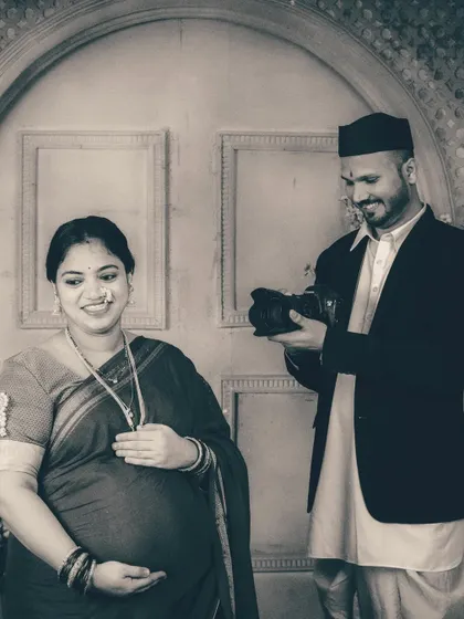 A candid black and white photo that freezes a moment of shared laughter. The monochrome style enhances the authenticity of their expressions during this creative studio maternity session.