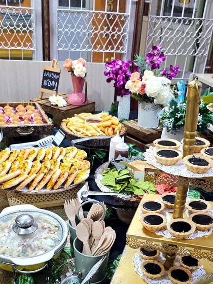 A full view of a birthday grazing table, featuring veggie pasta, chocolate tarts, mini pizzas, and french fries. It's a perfect mix of savory and sweet treats.