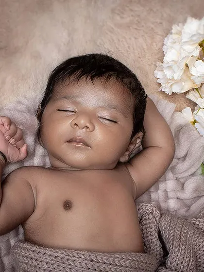 A peaceful close-up of a sleeping newborn, with a focus on their serene expression. The neutral tones of the blanket and background keep the image soft and classic.
