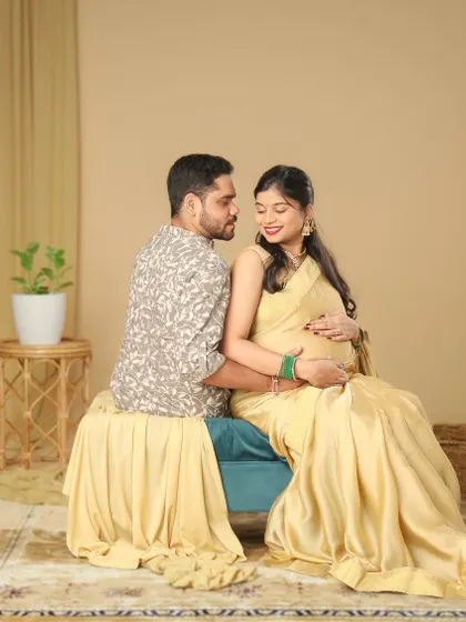 A beautiful, candid moment between a couple during their ethnic maternity shoot. Seated together in a lifestyle studio setup, they share a look of love and happiness.