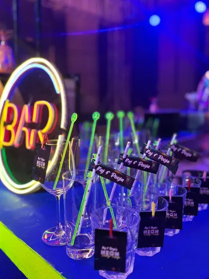 We personalize every detail. For Raj and Pooja's neon-themed party, we created custom stirrers and tags for their glasses, ensuring their names were part of the celebration.