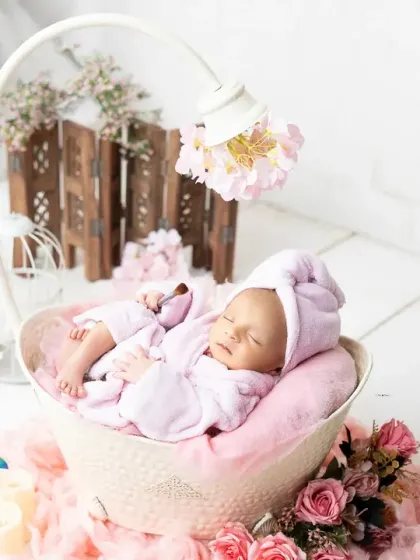 A serene moment from a newborn spa session, where the baby is peacefully asleep in a soft pink robe. I focus on creating a calm environment for these delicate shoots.