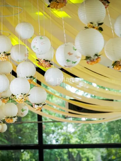 A close-up of the ceiling installation, featuring clusters of white paper lanterns decorated with delicate flowers and butterflies. This detail added a layer of whimsy and light to the entire space.