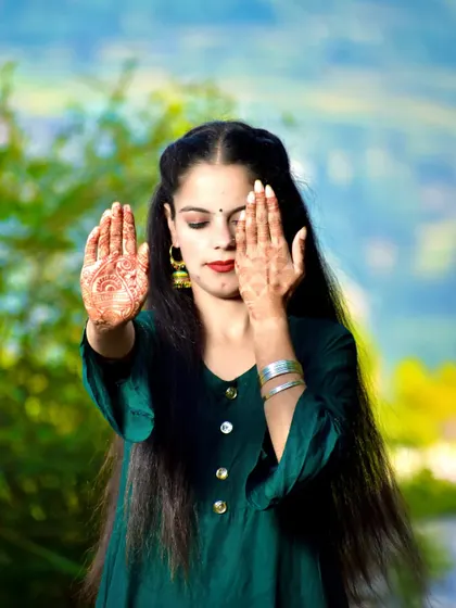 An artistic pose where the bride-to-be playfully covers one eye, drawing attention to her beautiful mehndi.