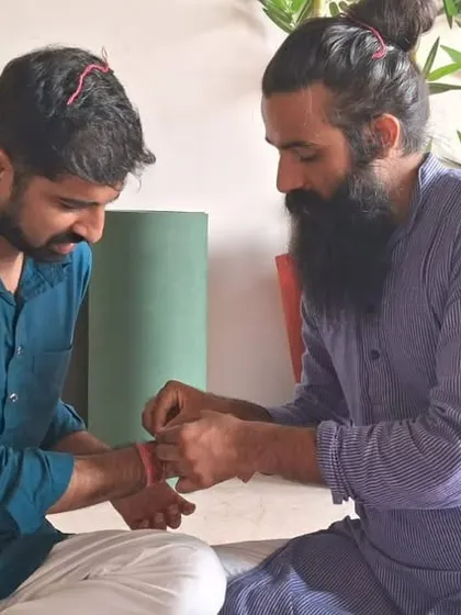 The tying of a sacred thread, or Kalava, during a ceremony. This is a symbol of protection and a reminder of the spiritual intentions set during the ritual.