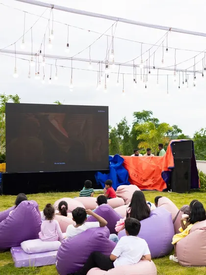 An outdoor movie night setup with a large screen and comfy beanbag chairs for guests. This is a perfect idea for a relaxed birthday celebration or a fun family gathering.
