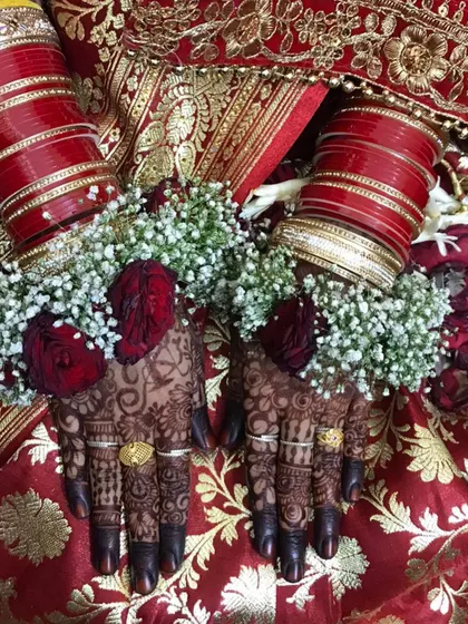 The bride's hands adorned with floral jewelry, highlighting the beautiful dark mehendi stain.