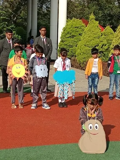 A student playing the role of a seed crouches down, waiting for the elements to help it grow in this educational performance.