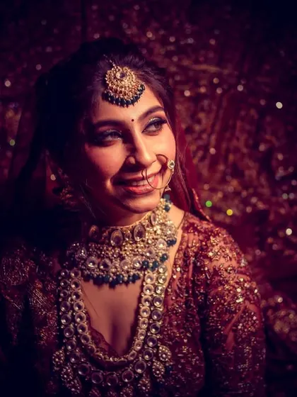 A beautiful, smiling bridal portrait, captured with dramatic lighting that makes her jewelry sparkle.