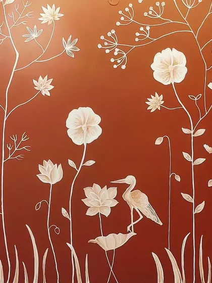 A close-up of a 3D texture mural on a rich, terracotta-colored wall in a Bangalore home. The white raised florals and a delicate crane create a beautiful contrast and a serene, nature-inspired scene.