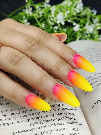 A full look at the vibrant neon ombré nail art, featuring a gradient of hot pink, orange, and yellow. This sizzling trend is perfect for anyone who wants to stand out and shine bright.