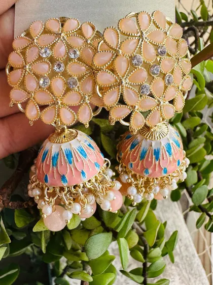 For a soft, pastel look, these peach-colored jhumkas are a great choice. The dome features delicate blue and pink brushstrokes, offering a subtle pop of color.