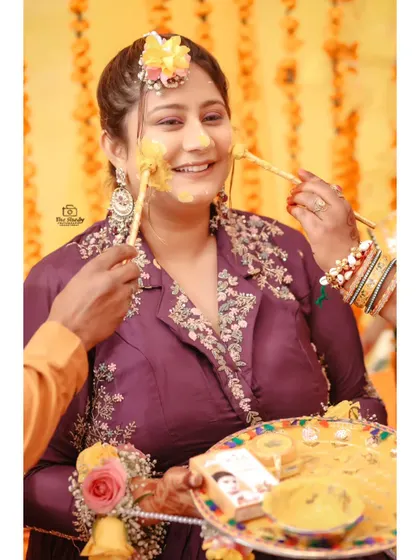 A sweet moment during the Haldi ritual, as the bride gets haldi applied by her loved ones. Her happy smile says it all.