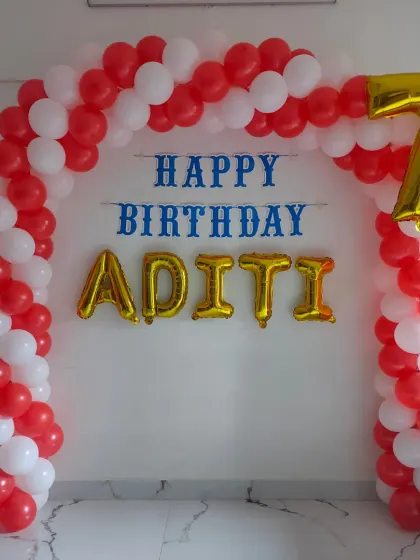 A simple red and white balloon arch with personalized name and age balloons, great for creating an entrance or backdrop at home.