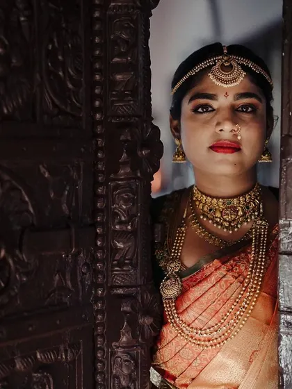 A striking bridal portrait, with the bride peeking through a beautifully carved wooden door. The play of light and shadow adds a touch of mystery and artistry to the image.
