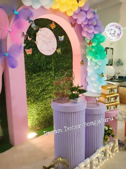 A 'Half way to one' celebration with a pink and purple butterfly theme, featuring a grass wall backdrop.