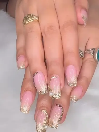 Stunning bridal nails featuring a soft ombré base with extravagant gold glitter, chrome, and pearl embellishments.