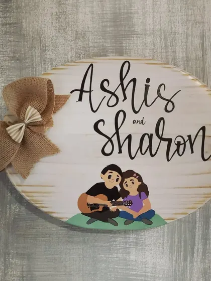 The "Ashis and Sharon" name plaque against a textured wall. The white-washed wood finish gives it a lovely rustic charm.